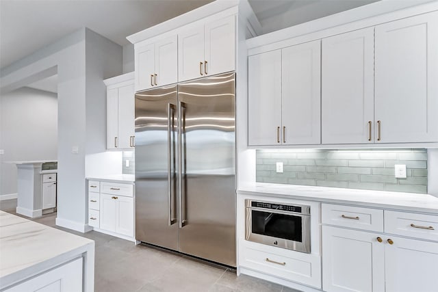 kitchen featuring light tile patterned floors, stainless steel appliances, backsplash, and white cabinets