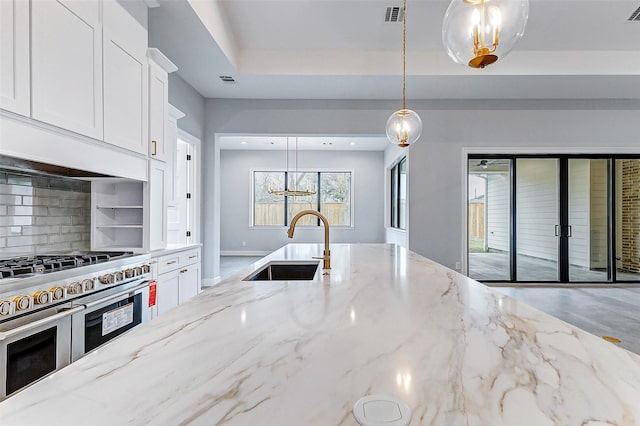 kitchen featuring a sink, white cabinetry, visible vents, double oven range, and a tray ceiling