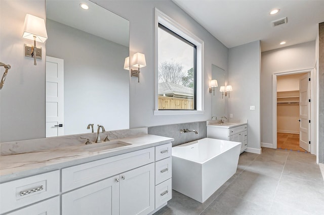 bathroom featuring visible vents, two vanities, a sink, and recessed lighting