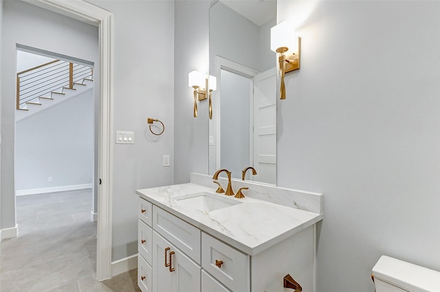 half bathroom with baseboards, vanity, and toilet