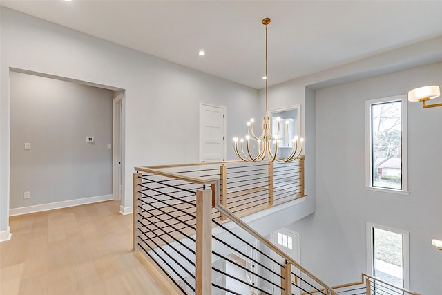 corridor with baseboards, light wood-style flooring, an inviting chandelier, an upstairs landing, and recessed lighting