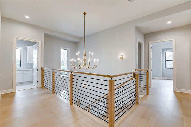 hallway with recessed lighting, light wood-type flooring, an upstairs landing, and an inviting chandelier