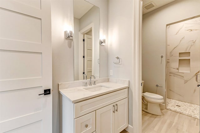 full bathroom featuring toilet, wood finished floors, visible vents, vanity, and a shower stall