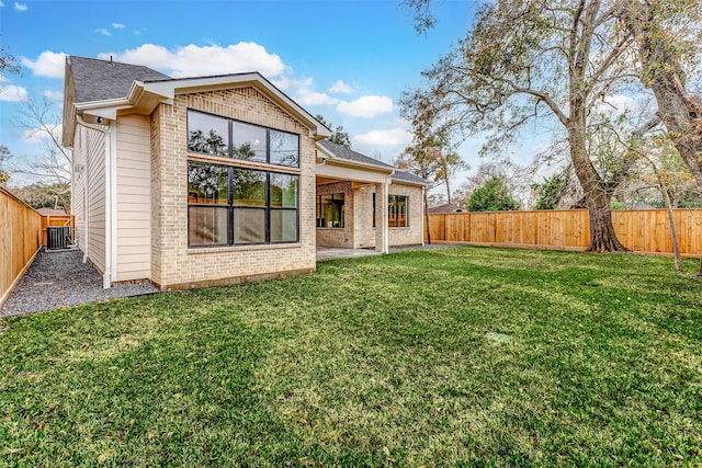 back of house with a fenced backyard and brick siding