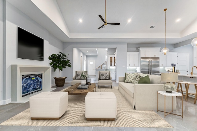 living room featuring a fireplace with raised hearth, baseboards, visible vents, and recessed lighting