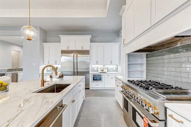 kitchen with a sink, high quality appliances, white cabinets, custom exhaust hood, and decorative backsplash