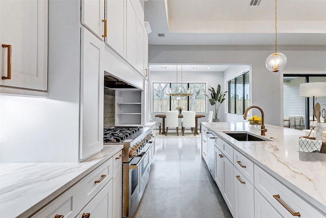 kitchen featuring range with two ovens, white cabinets, a sink, and decorative light fixtures