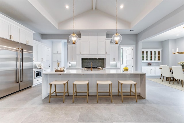 kitchen with a large island, light countertops, backsplash, white cabinets, and stainless steel built in fridge