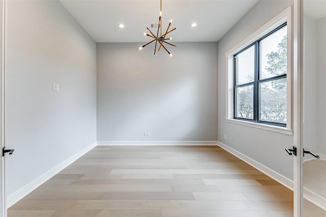 unfurnished room with baseboards, recessed lighting, an inviting chandelier, and light wood-style floors