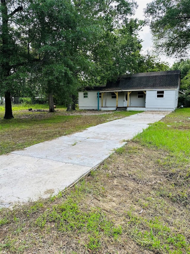 view of front facade featuring a shingled roof and concrete driveway