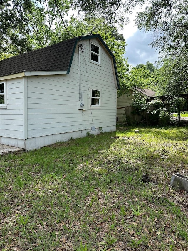 view of side of home with a yard, roof with shingles, and a gambrel roof