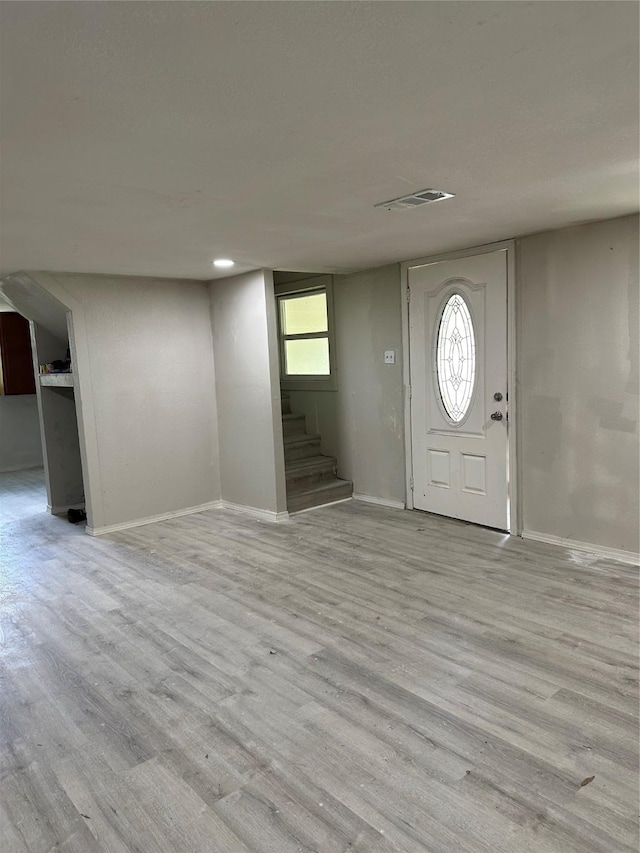 entrance foyer featuring visible vents, stairway, baseboards, and wood finished floors