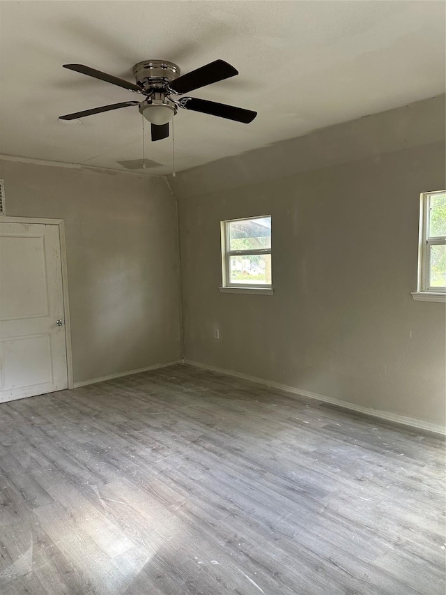 spare room with a wealth of natural light, visible vents, baseboards, and wood finished floors