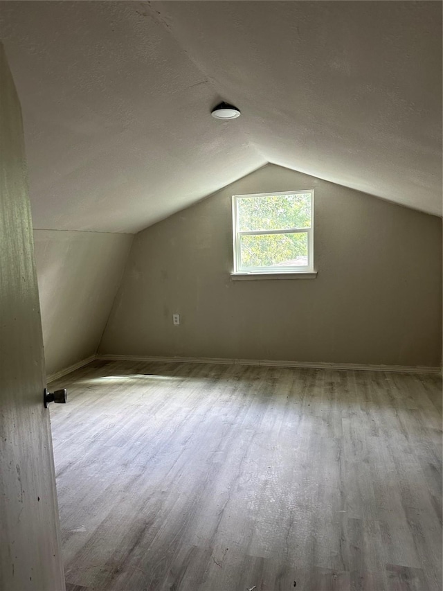 bonus room with lofted ceiling, a textured ceiling, and wood finished floors