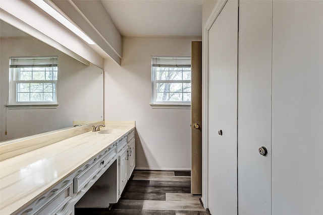 bathroom featuring baseboards, wood finished floors, and vanity