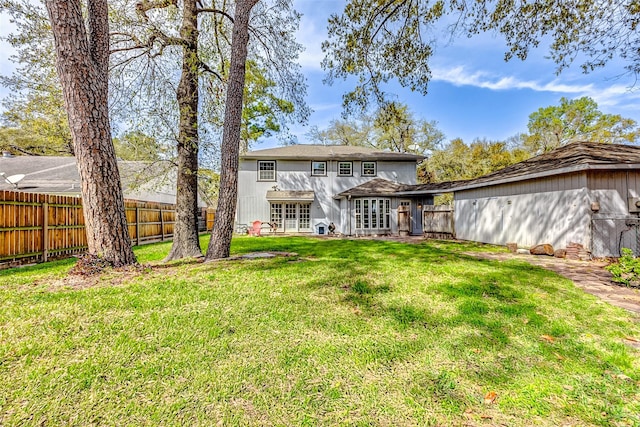 rear view of house featuring a lawn, french doors, and a fenced backyard