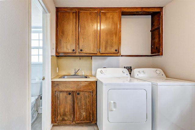 clothes washing area featuring a sink, cabinet space, and separate washer and dryer