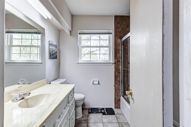 bathroom featuring tile patterned floors, toilet, a healthy amount of sunlight, and vanity