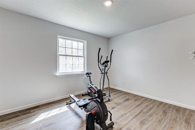 workout area with a textured ceiling, baseboards, and wood finished floors