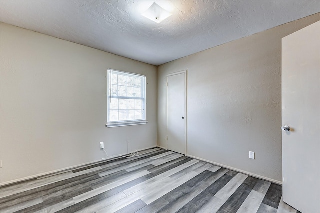 unfurnished bedroom with a closet, a textured ceiling, and wood finished floors