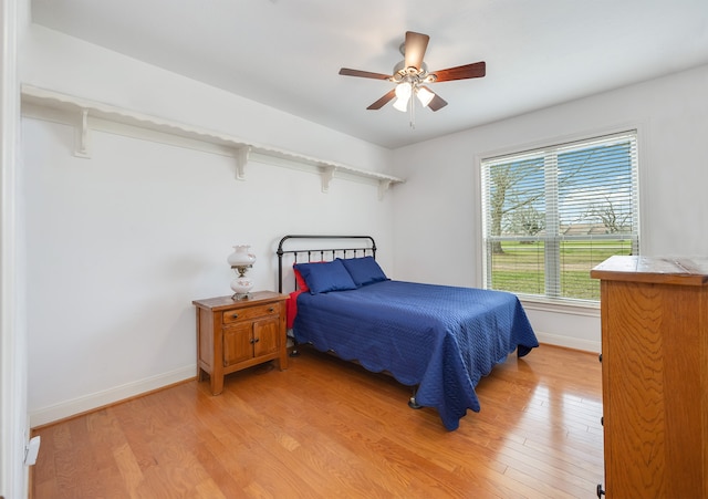 bedroom featuring light wood-style flooring, baseboards, and ceiling fan