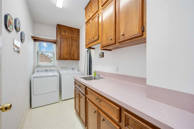 laundry area featuring a sink, cabinet space, light floors, and washer and clothes dryer