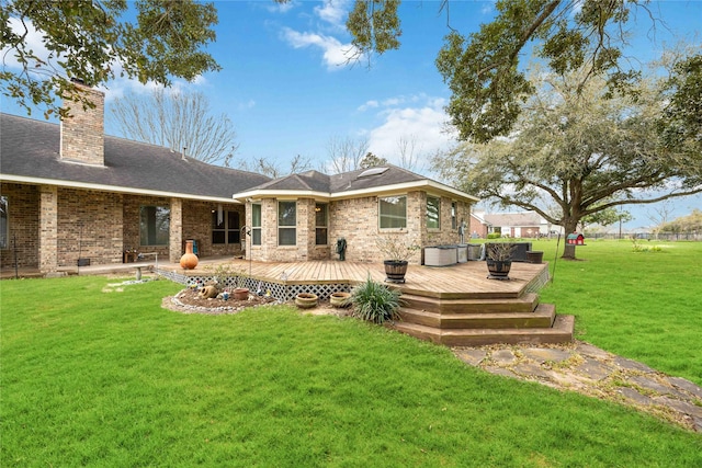 rear view of property with a deck, a yard, a shingled roof, brick siding, and a chimney