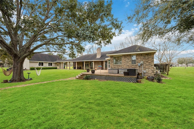 back of property featuring a wooden deck, a lawn, a chimney, and brick siding