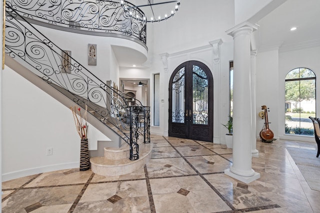 entrance foyer with crown molding, stairs, baseboards, and decorative columns