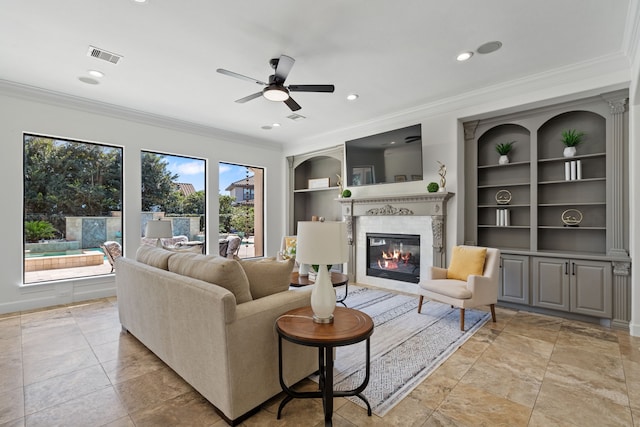 living area featuring a glass covered fireplace, crown molding, built in features, and visible vents