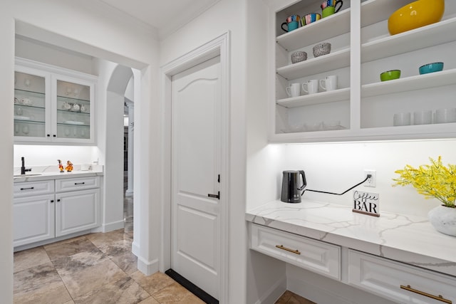 interior space with arched walkways, crown molding, baseboards, and a sink