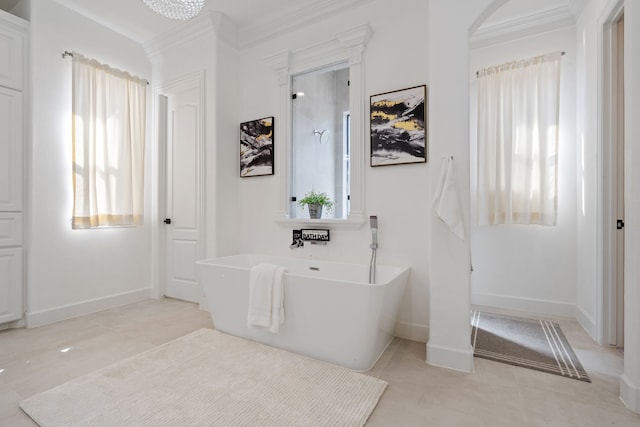 bathroom featuring a chandelier, a freestanding bath, baseboards, and ornamental molding