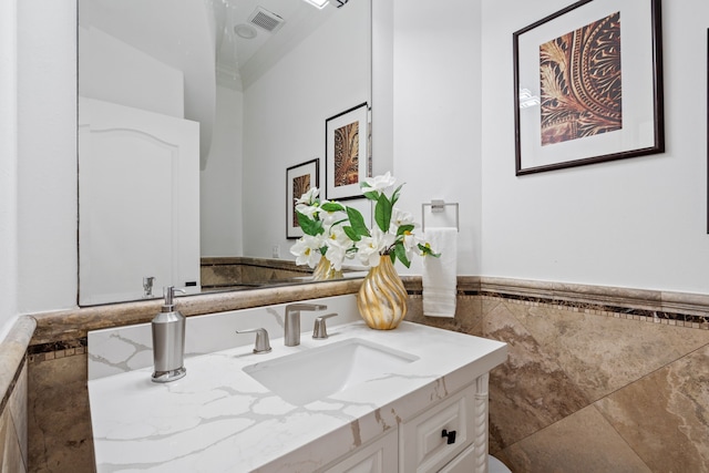 bathroom featuring vanity, tile walls, a wainscoted wall, and visible vents