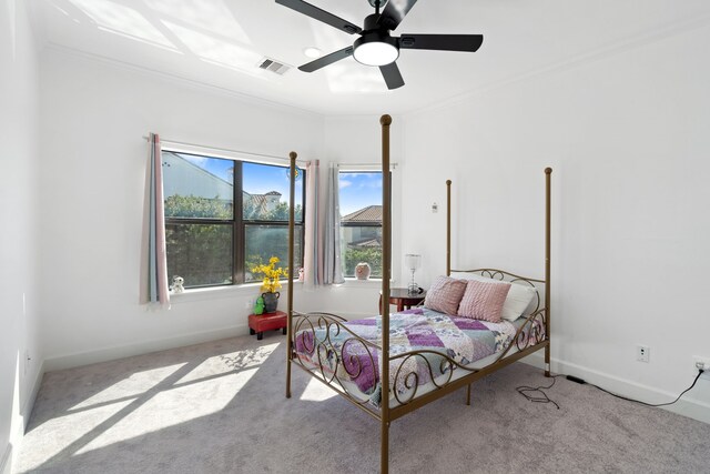 carpeted bedroom with crown molding, baseboards, visible vents, and ceiling fan