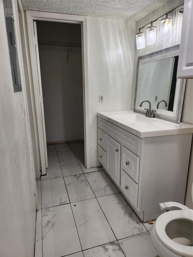 bathroom with electric panel, toilet, marble finish floor, a textured ceiling, and vanity