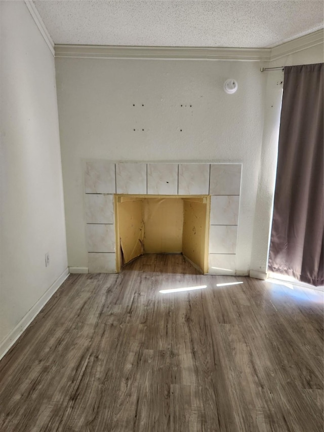 room details featuring ornamental molding, a textured ceiling, baseboards, and wood finished floors