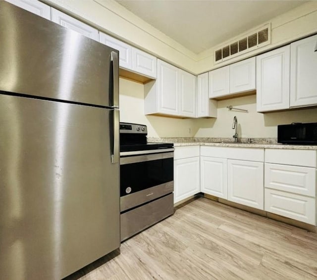 kitchen featuring light wood finished floors, visible vents, white cabinets, appliances with stainless steel finishes, and a sink