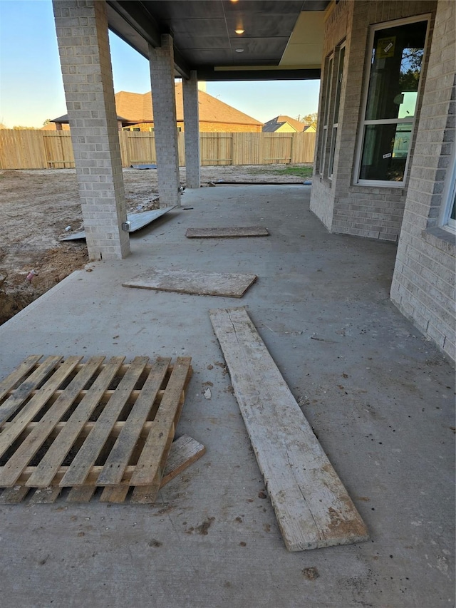 patio terrace at dusk featuring a fenced backyard