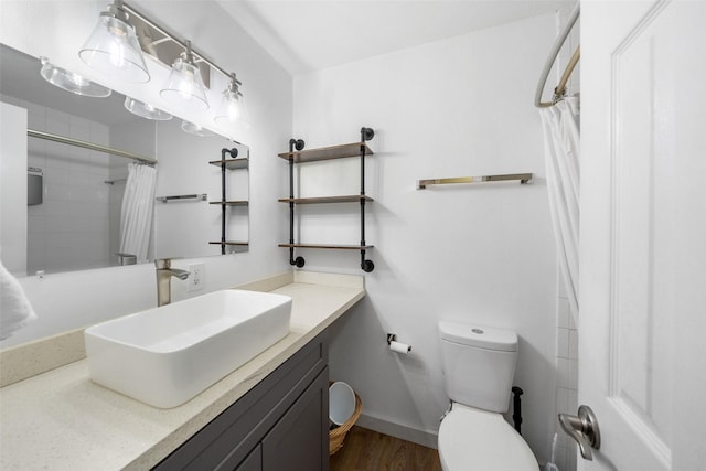 bathroom with curtained shower, toilet, wood finished floors, vanity, and baseboards