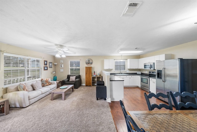 living area with a ceiling fan, visible vents, and wood finished floors