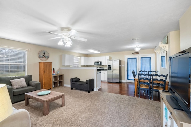 living room with dark colored carpet, visible vents, ceiling fan, and baseboards