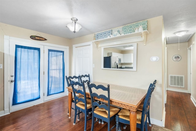 dining space with baseboards, attic access, visible vents, and hardwood / wood-style floors