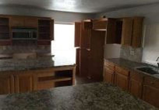 kitchen with brown cabinetry, a sink, and open shelves