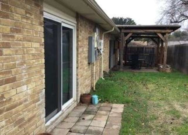 view of side of home with a patio, brick siding, and fence