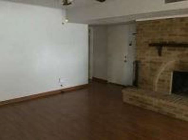 unfurnished living room featuring a fireplace, wood finished floors, and baseboards