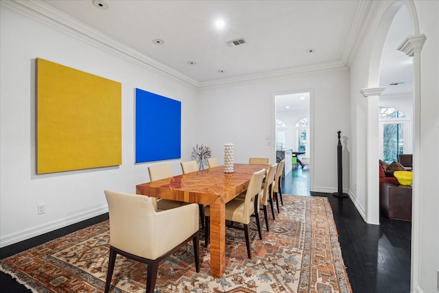 dining room featuring baseboards, visible vents, ornamental molding, wood finished floors, and ornate columns