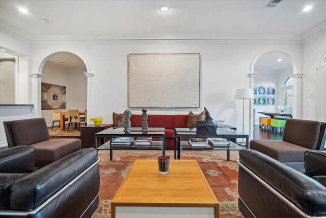 living room with ornate columns, crown molding, arched walkways, and wood finished floors