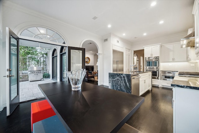 dining area with arched walkways, crown molding, dark wood finished floors, recessed lighting, and visible vents