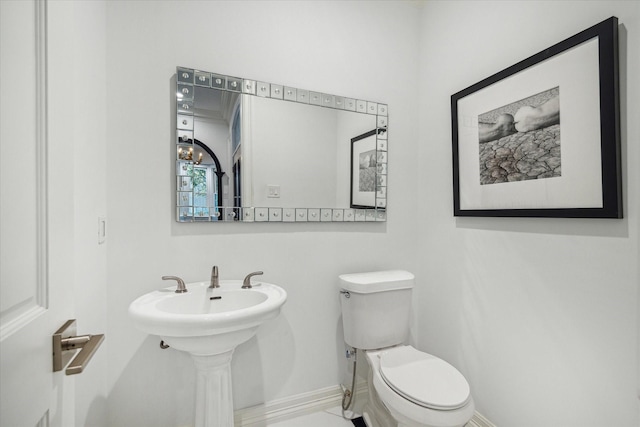 half bath with baseboards and toilet