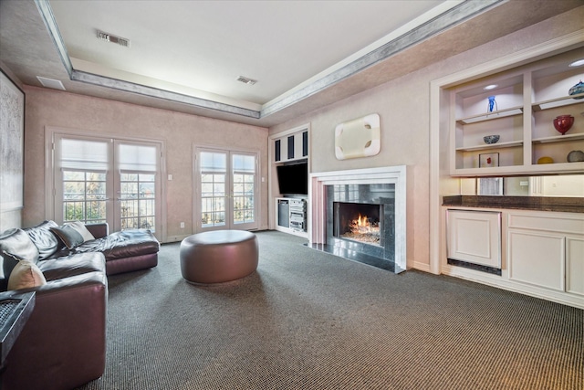 carpeted living room featuring built in features, french doors, visible vents, a premium fireplace, and baseboards